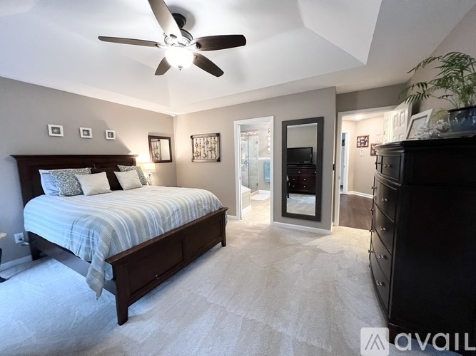 A bedroom with a bed, dresser, and ceiling fan.