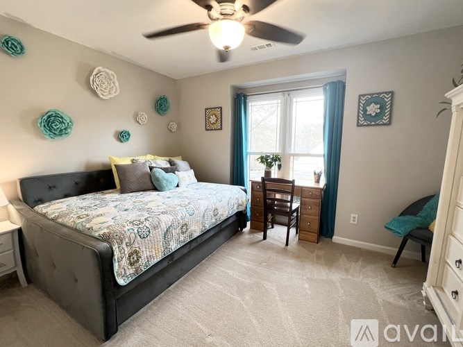 A bedroom with a bed, dresser, and ceiling fan.
