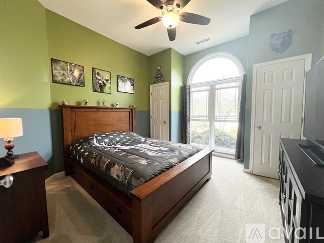 A bedroom with a bed, dresser, and ceiling fan.