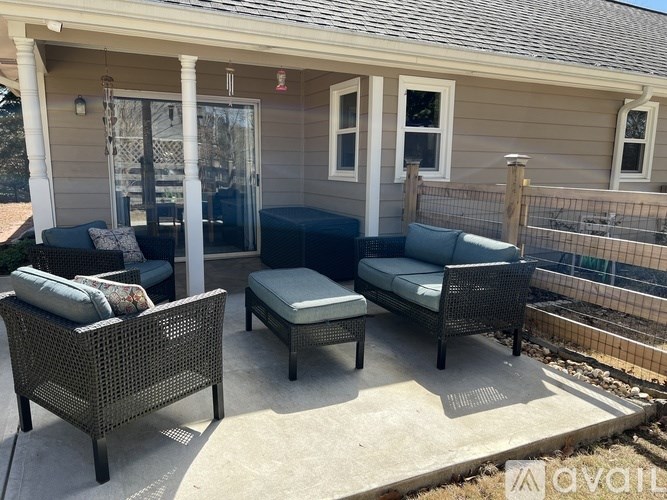 A patio with a couch, chair, and ottoman.