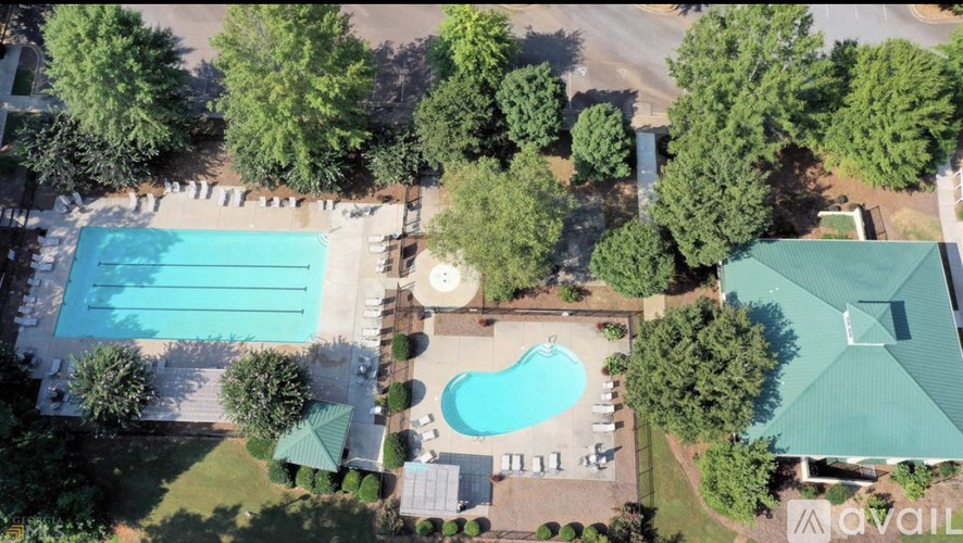 An aerial view of a swimming pool surrounded by trees and a building.