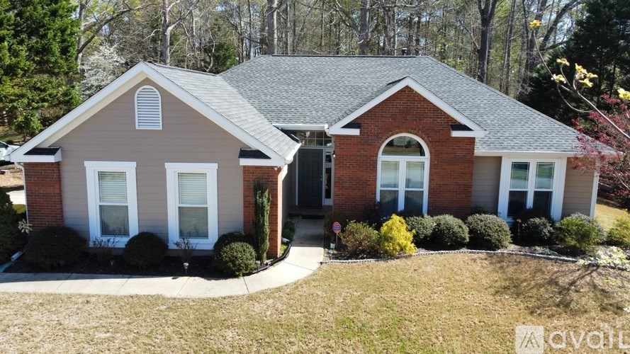A house with a red brick exterior and a grey roof is for sale.