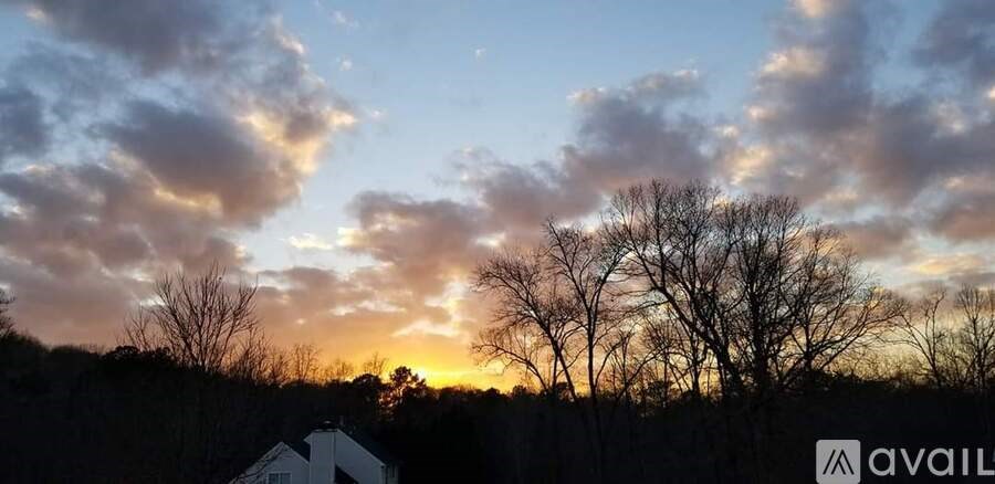 A house is visible in the foreground with a sunset in the background.