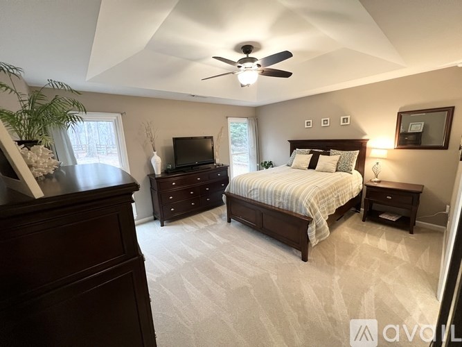 A bedroom with a bed, dresser, and ceiling fan.