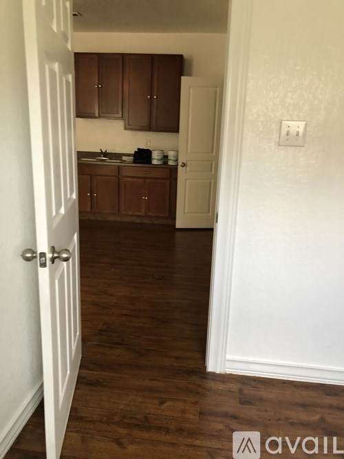 A white door is open to a kitchen with brown cabinets.