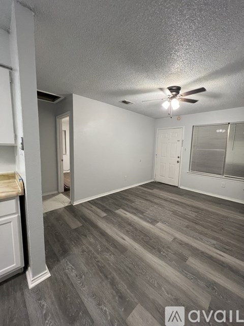 A room with a ceiling fan and wooden flooring.