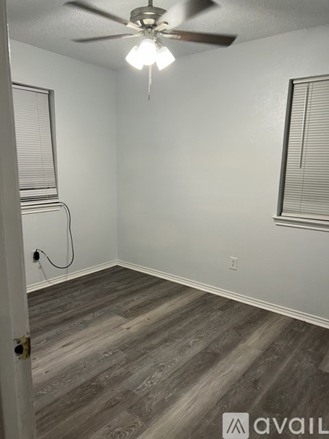 A room with a ceiling fan and a door on the left.