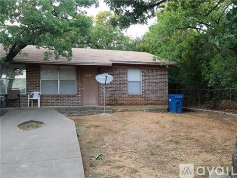 A house with a brown roof and a blue trash can in front.