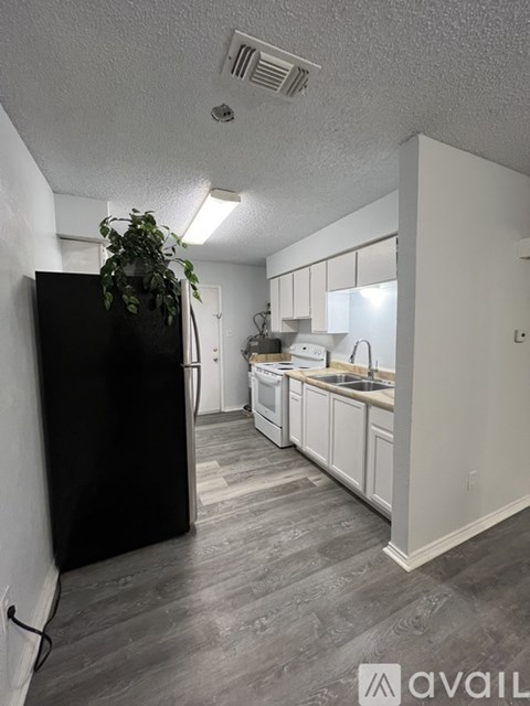 A kitchen with a black refrigerator and white cabinets.