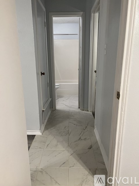 A hallway with marble flooring and white walls.