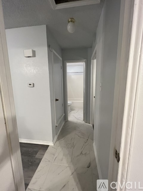 A long white hallway with marble floors and white walls.