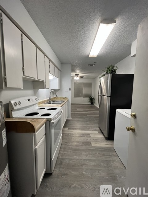 A kitchen with white cabinets and a black refrigerator.