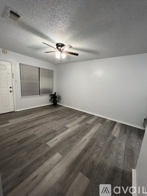 A room with a ceiling fan and wooden flooring.
