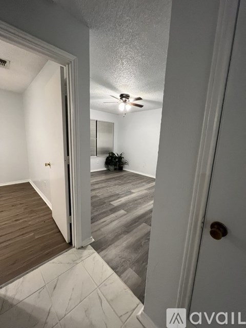 A hallway with a wooden floor and a ceiling fan.