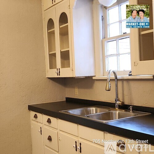 A kitchen with white cabinets and a black countertop.
