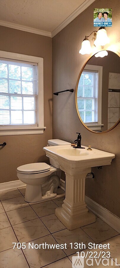 A bathroom with a toilet, pedestal sink and mirror.