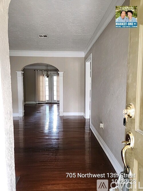 A hallway with wood floors and a door on the right.