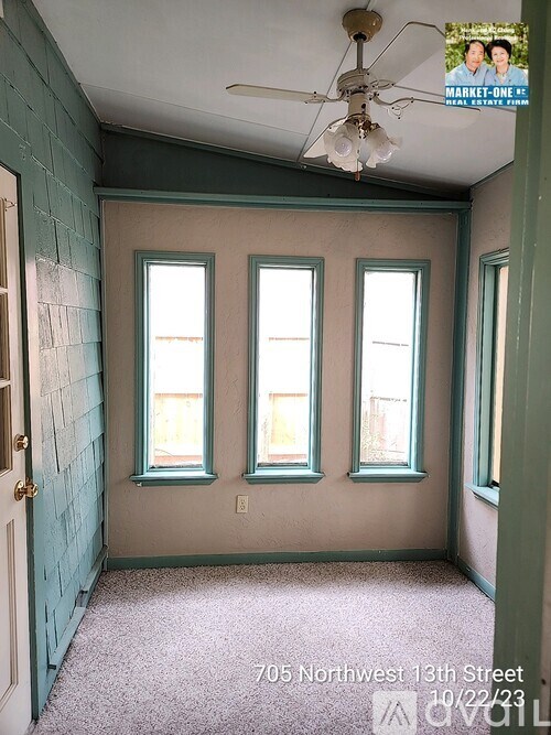 A room with a ceiling fan and three windows.