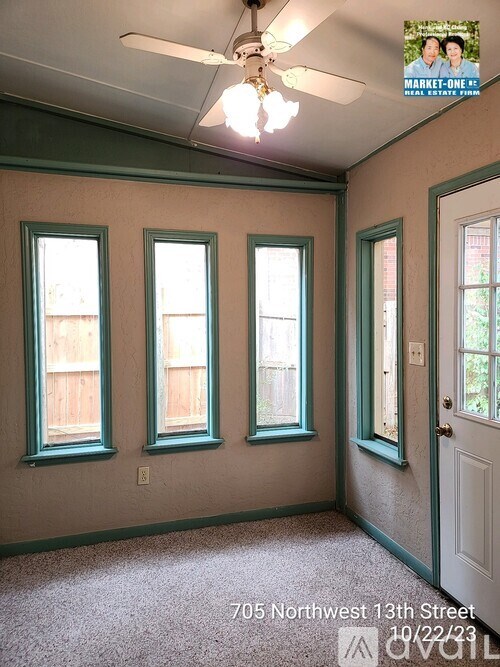 A room with a ceiling fan and three windows.