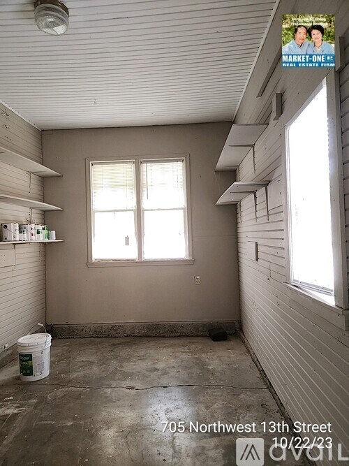 A room with a bucket on the floor and a sign that says "705 Northwest 13th Street 10/22/23".
