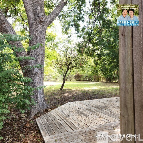 A wooden boardwalk leads through a green park.
