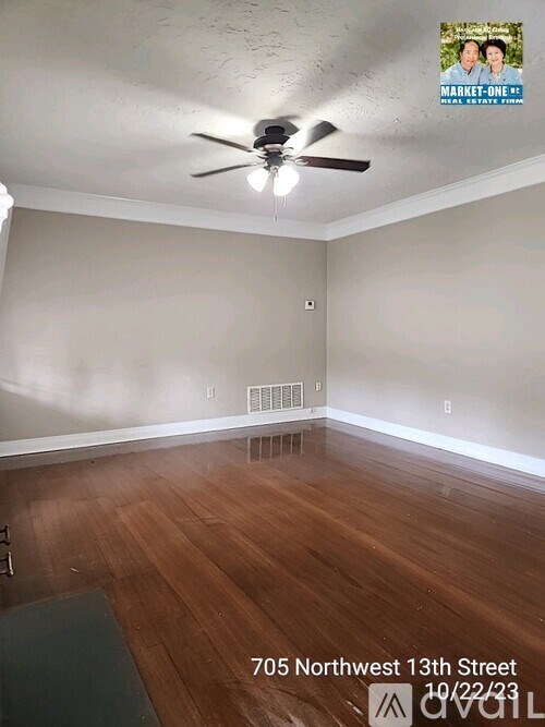 A room with a ceiling fan and wooden flooring.