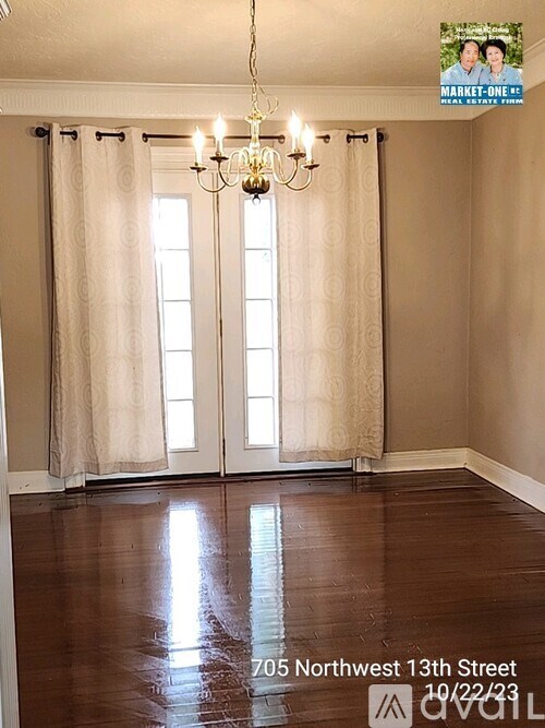 A room with a chandelier and a window with curtains.