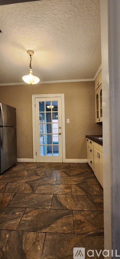A kitchen with a tiled floor and a refrigerator.