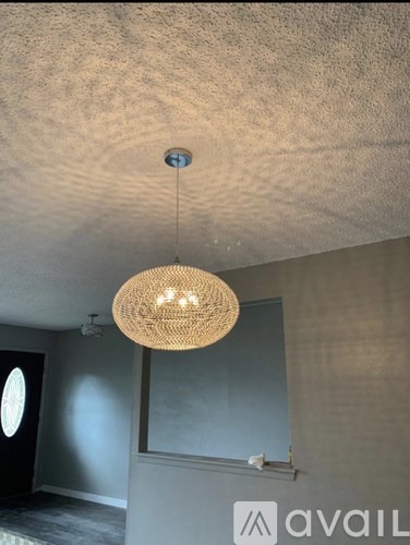 A room with a hanging light fixture and a window.