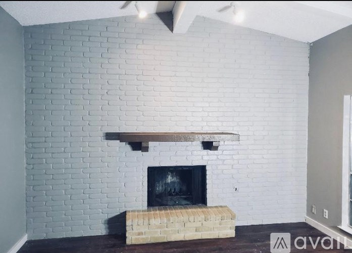 A white brick fireplace with a wooden mantle and a brick hearth.