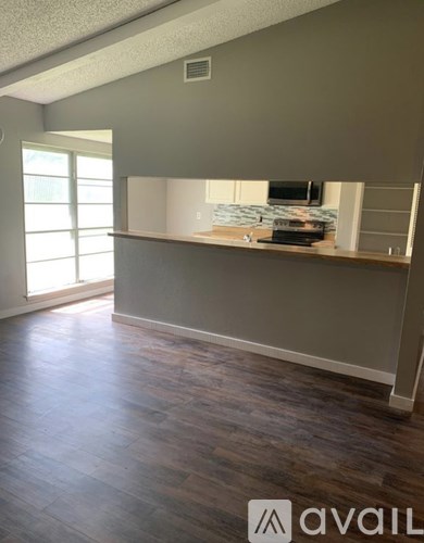 A room with wooden flooring and a window letting in natural light.