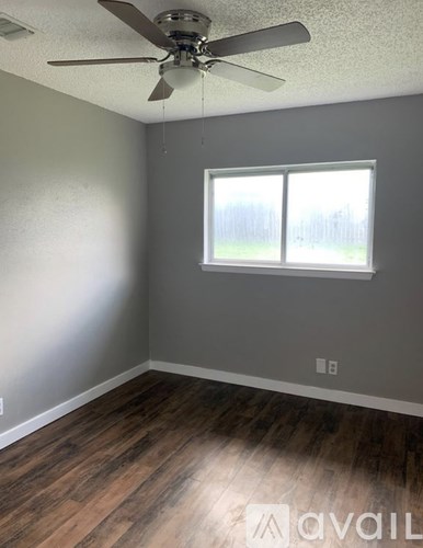 A room with a ceiling fan and wooden flooring.