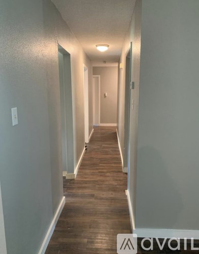 A long hallway with wood floors and white walls.