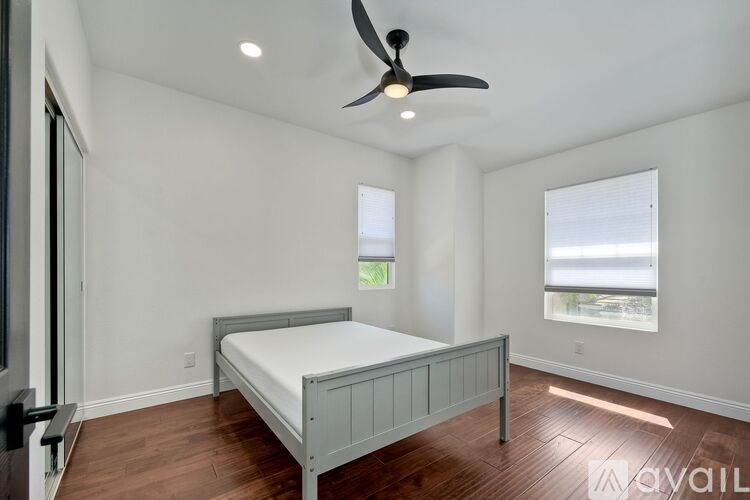 A bedroom with a bed, a ceiling fan, and a window.
