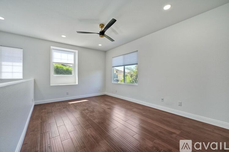 A room with a ceiling fan and two windows.