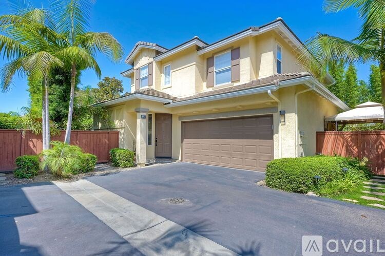 A house with a driveway and palm trees in front.