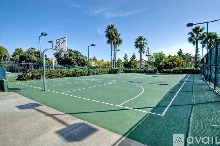 A tennis court surrounded by palm trees and a fence.