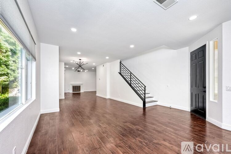 A spacious room with wooden floors and a staircase.