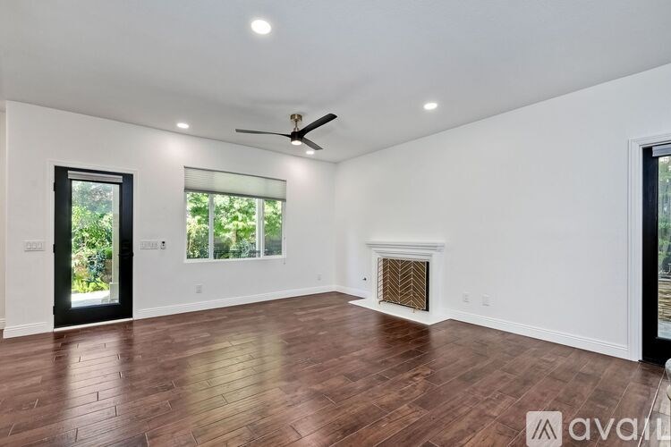 A spacious room with wood flooring and a ceiling fan.