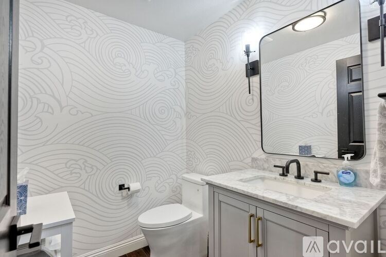 A bathroom with a toilet, sink, and mirror.