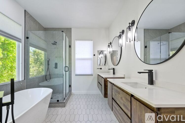 A modern bathroom with a white tub, sink, and mirror.