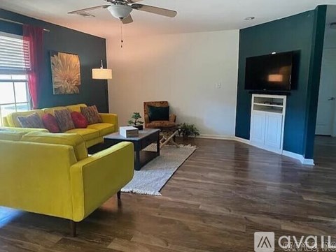 A living room with a yellow couch and a ceiling fan.