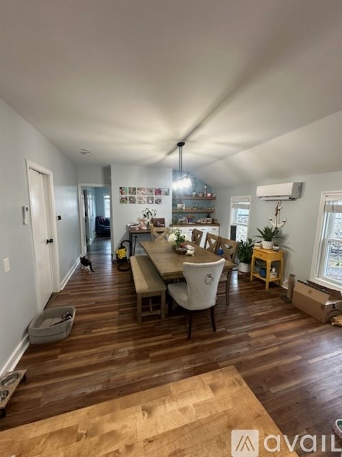 A room with wooden floors and furniture, including a dining table with chairs.