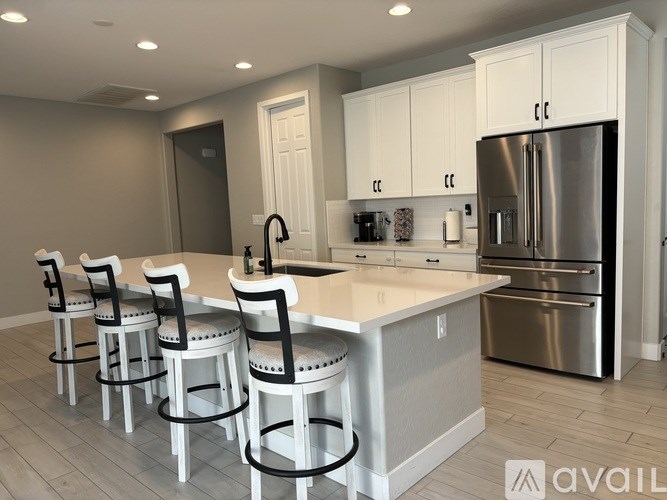A kitchen with white cabinets and a stainless steel refrigerator.