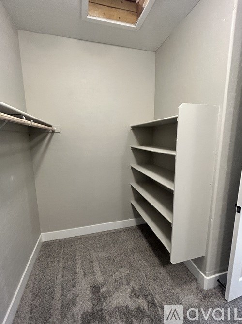 A small storage room with a white shelving unit and a grey carpet.