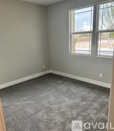 A room with a carpeted floor and two windows.