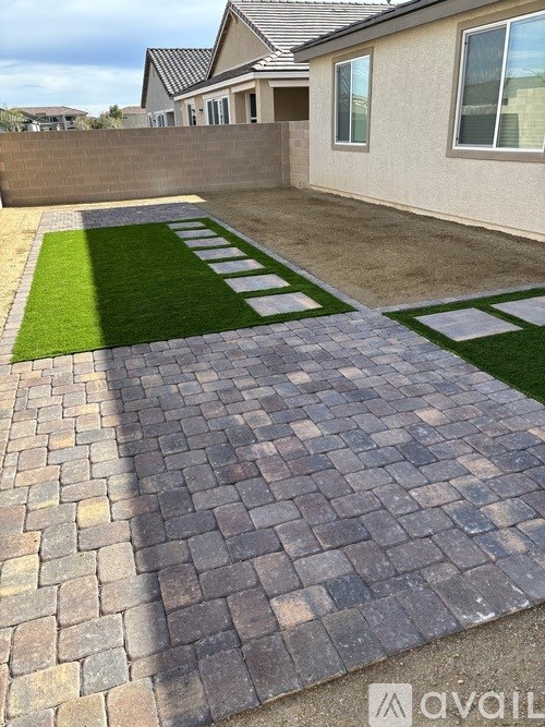 A patio with a brick walkway and a green lawn.
