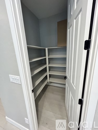 A white closet with shelves and a door.