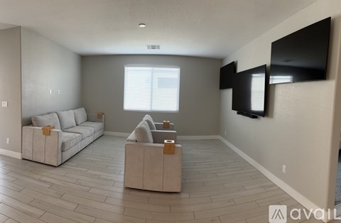 A living room with a grey couch and a television on the wall.