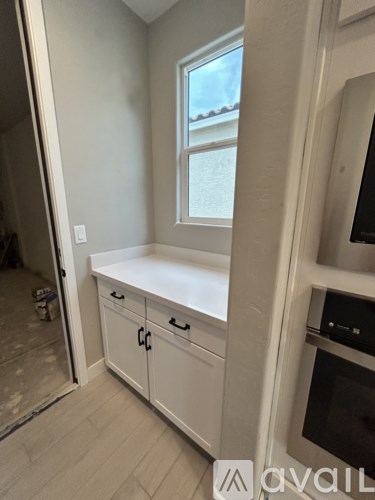 A kitchen with white cabinets and a window.